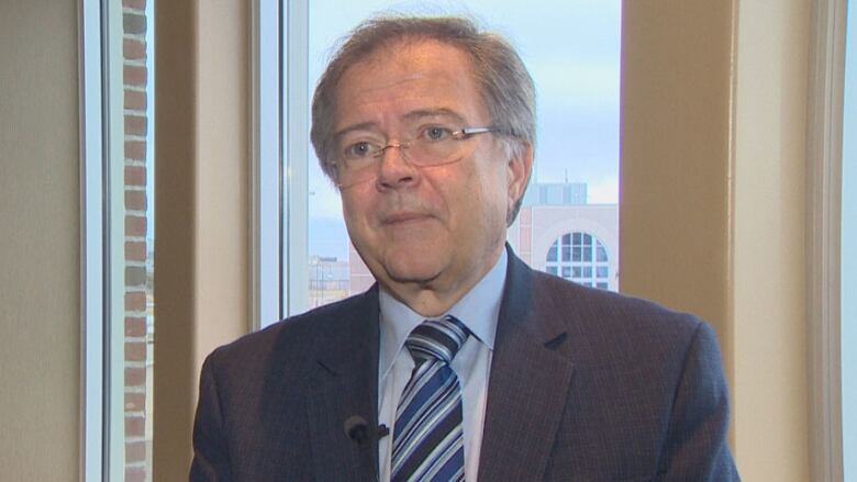 A man in a dark suit wearing glasses. 