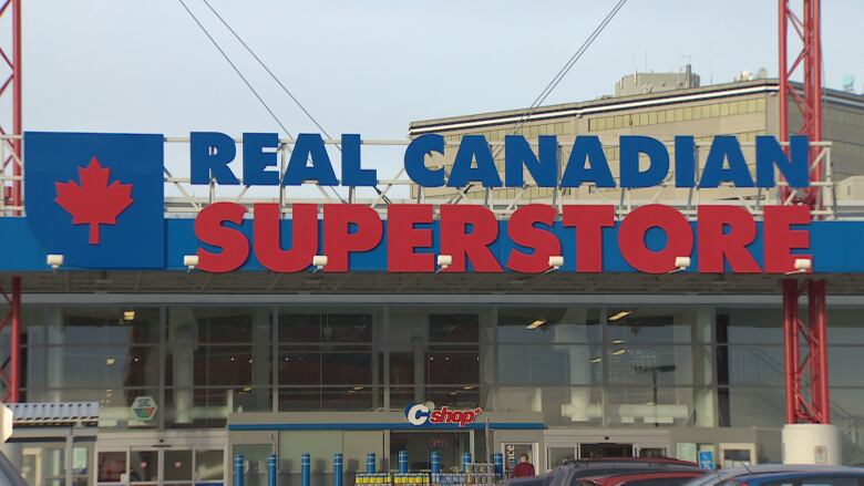 The entrance to a grocery store is seen from the parking lot. The name, Real Canadian Superstore, is visible above the entrance.