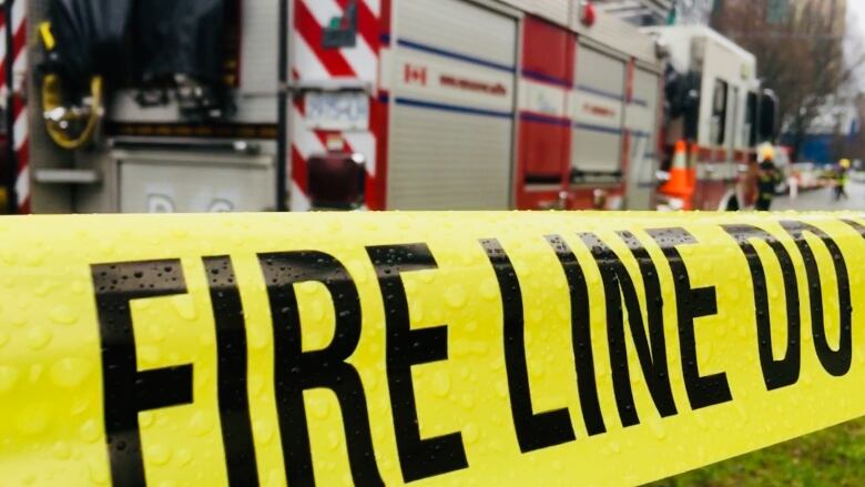 A Vancouver fire truck is seen on the street with yellow caution tape in the foreground that says fire line, do not cross.