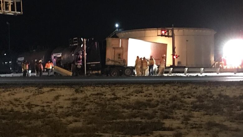 Damaged semi truck with people trying standing around it.