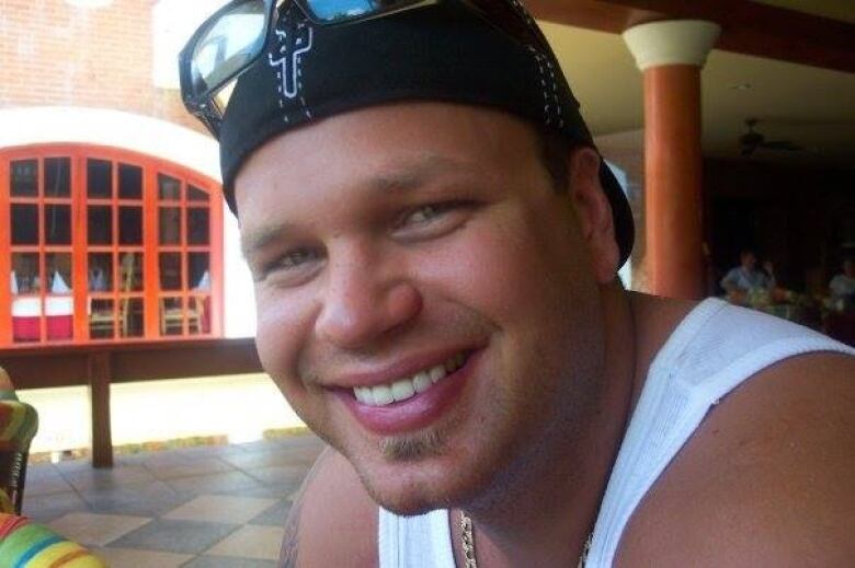 A close-up portrait of a man wearing a reversed ball cap.