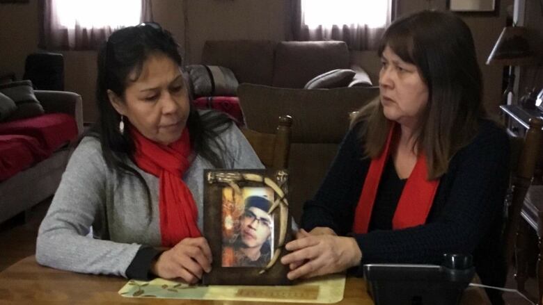 Micheline Knapaysweet (left) and Helen Knapaysweet (right) hold a photo of their family member Joey Knapaysweet between them.