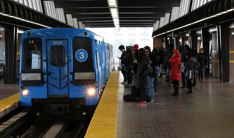 Blue light rail car sits in the station.