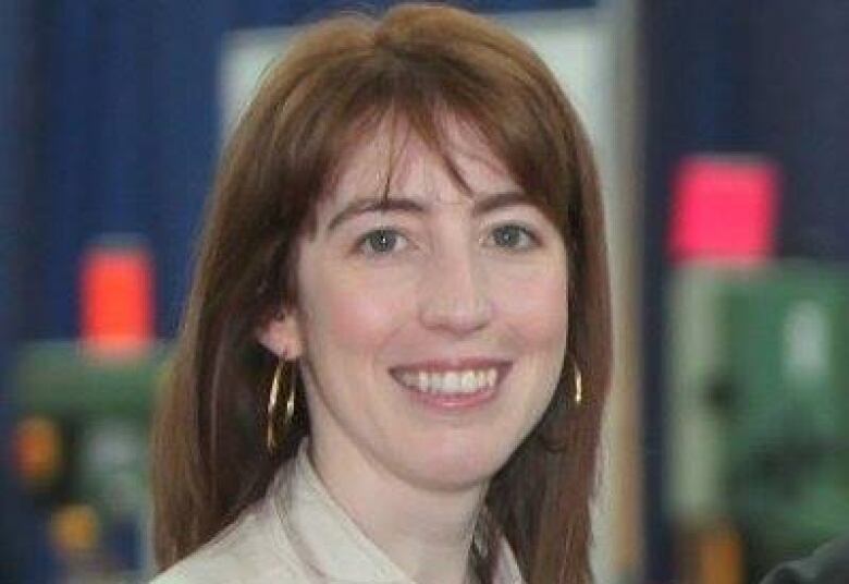 A woman with long red hair and big gold hoop earrings smiles for the camera.