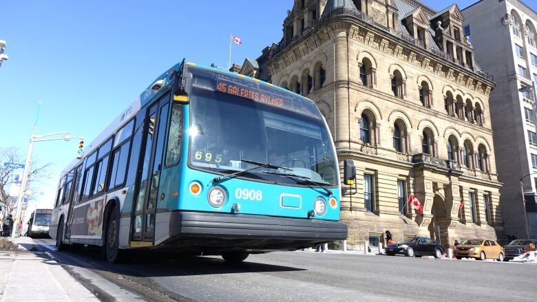 A blue city bus with a stone building in the background.