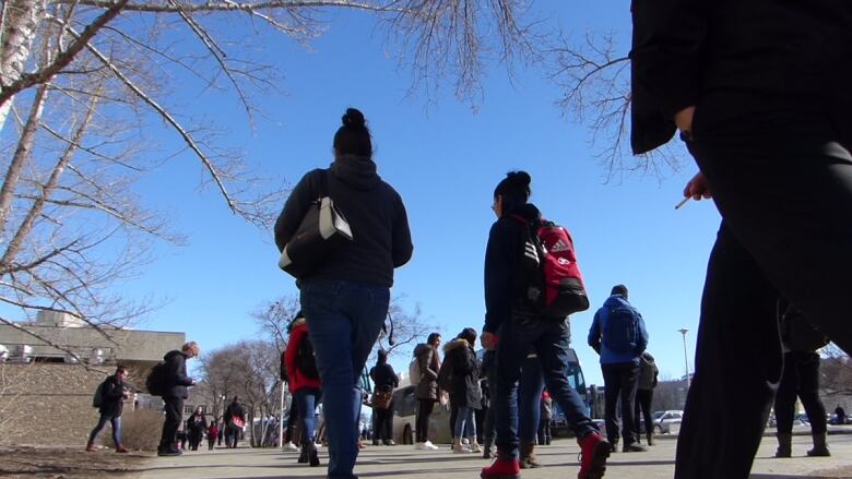 Dozens of students walking on a sidewalk