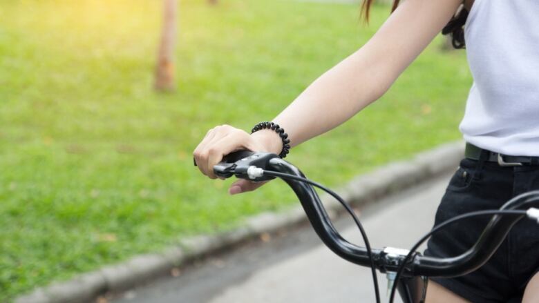 Girl's hands on bicycle handles.