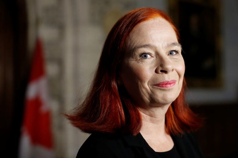 A woman standing in front of a Canadian flag.