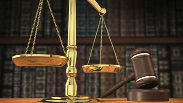 The scales of justice and a judge's gavel rest on a wooden desk.