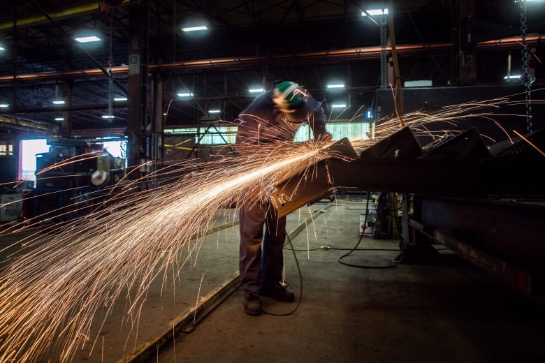 A steel worker uses a grinder on a steel stairs being manufactured for a high school.