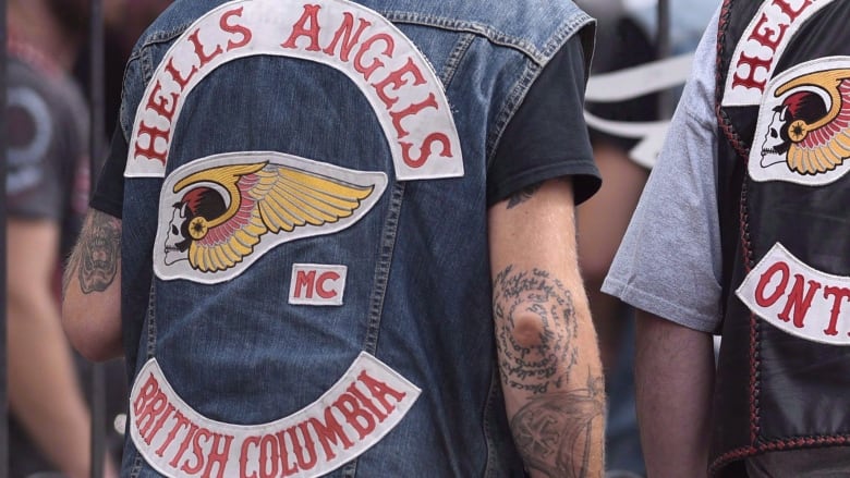 Two people wearing Hells Angels jackets are pictured with their back to camera.