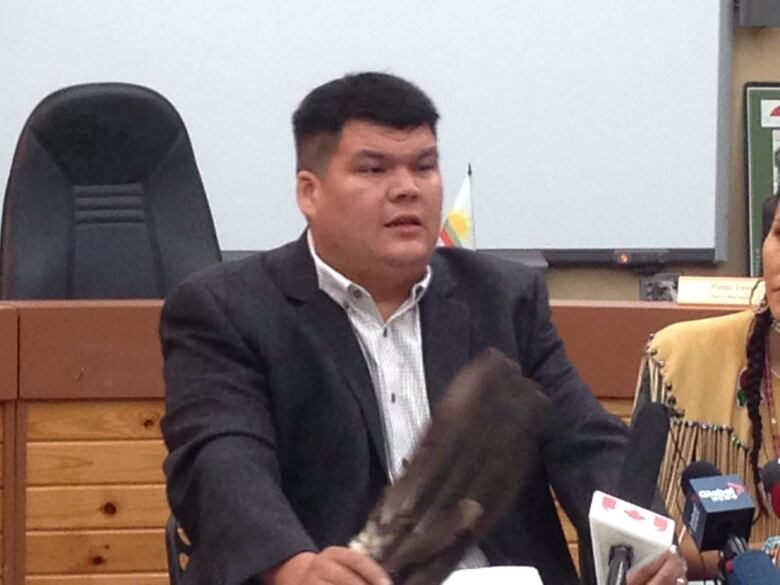 A Mi'kmaw chief holding up an eagle wing at a press conference. 