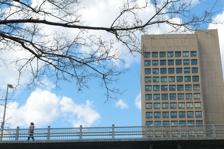 A man walks along the Laurier Avenue Bridge past the Major-General George R. Pearkes Building in Ottawa on May 5, 2018.