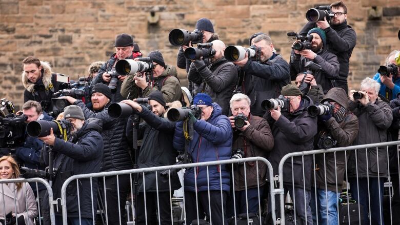 Many photographers take pictures from behind a gate. 