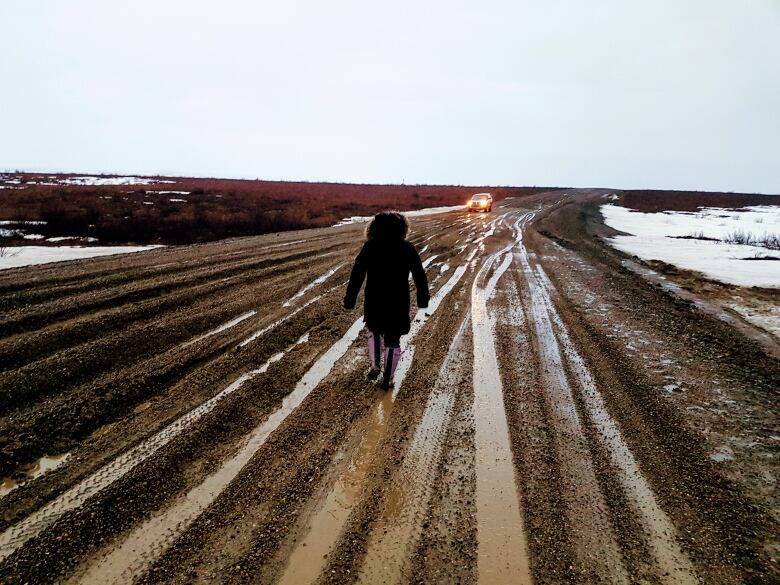 A person walks down the Inuvik Tuktoyaktuk Highway. It was closed due to rainy and muddy conditions in May 2018. 