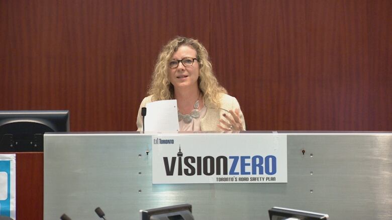 A woman speaks at a podium for Vision Zero.