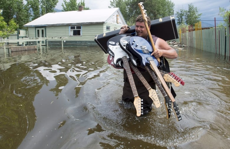 A man carries guitars through a flood,