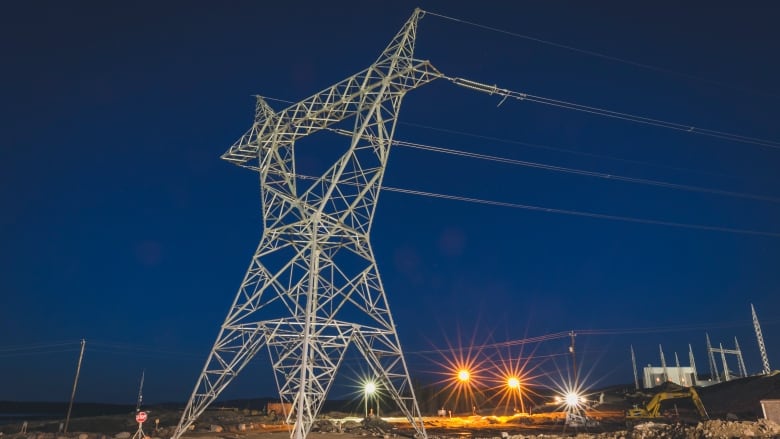 A transmission tower at night, powerful cables of the Labrador-Island Link stretching off into the distance.