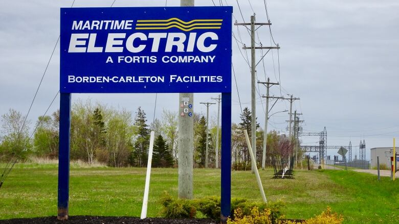 A sign for utility company Maritime Electric, with a line of utility poles in the background.