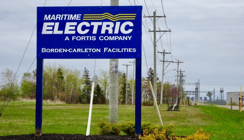 A sign for utility company Maritime Electric, with a line of utility poles in the background.