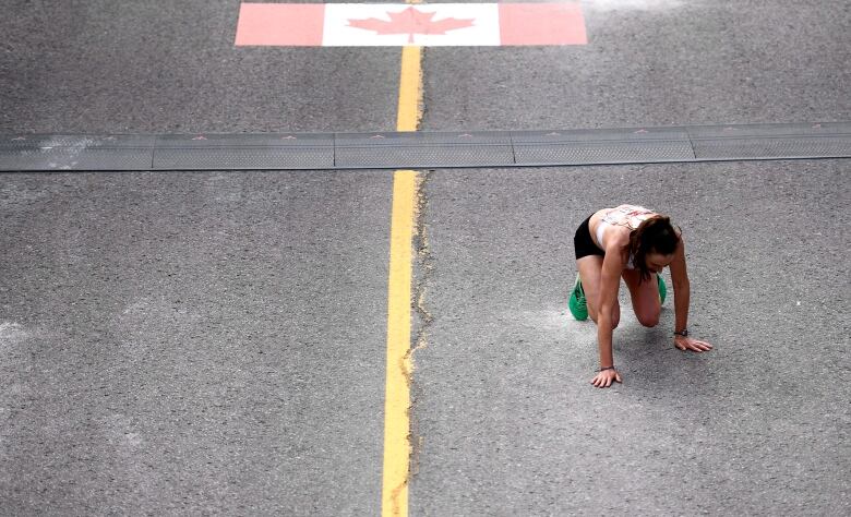 A runner crouches on the road.