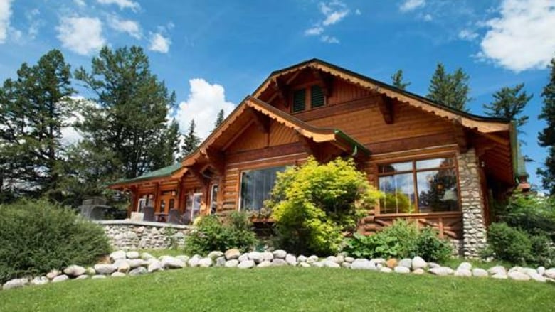 A warmly-coloured wood cabin surrounded by foliage on a sunny day