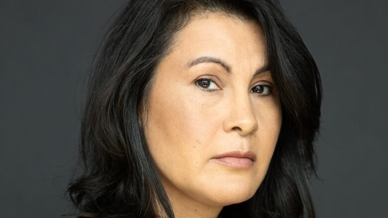 Portrait of a woman with dark hair and a beaded choker.