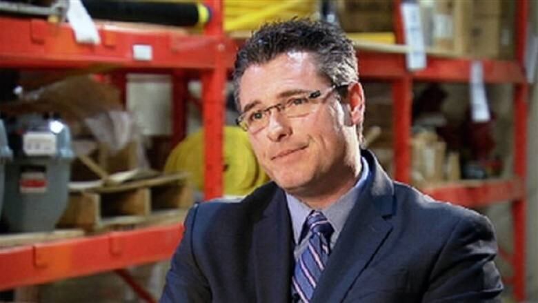 A man in a suit sits in a warehouse.