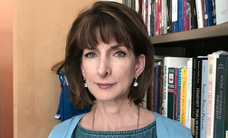 A woman with brown hair in front of a row of books. 