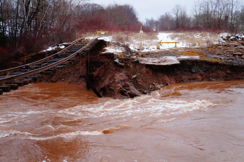 a rail line hangs over broken earth. 