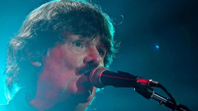 A closeup of a man singing into a microphone.