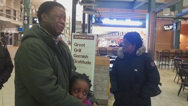 Father comforts tearful child at Edmonton airport.