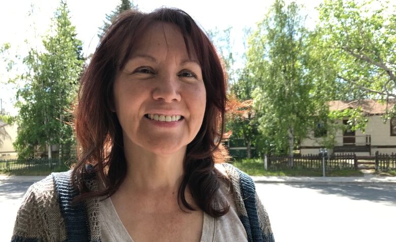 Brenda Norris stands in front of trees and buildings on a sunny day.