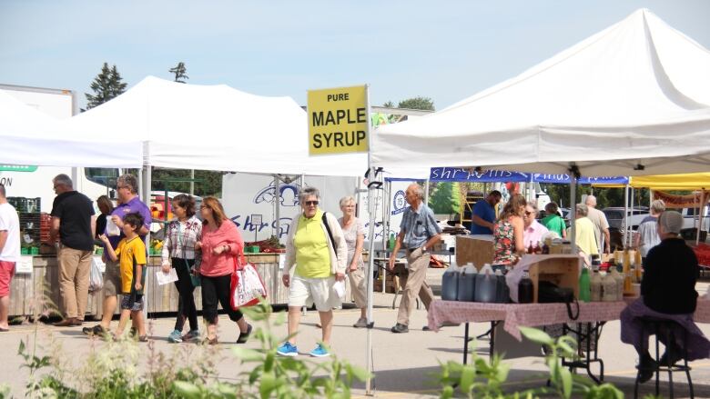 People walking at an outdoor farmers' market 