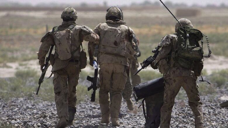 Canadian soldiers carry an injured comrade.