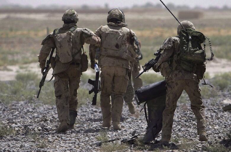 Canadian soldiers carry an injured comrade.