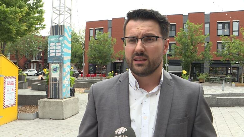 A man stands outside and speaks into a microphone. 