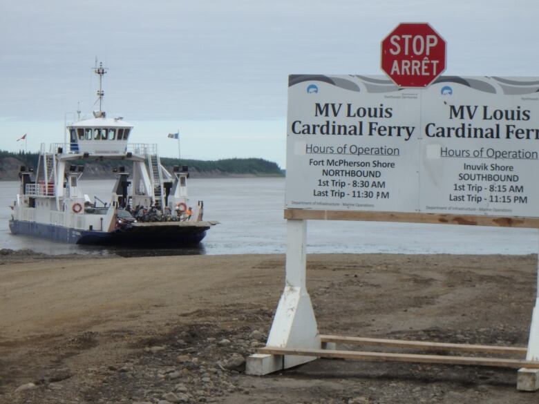 A ferry is seen in the water, behind a sign.