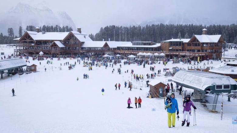 Lots of people are seen outside at a ski resort on an overcast day.