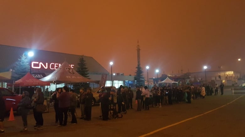 Wildfire evacuees line up for support in Prince George during wildfires in August 2018. The sky is dark orange.