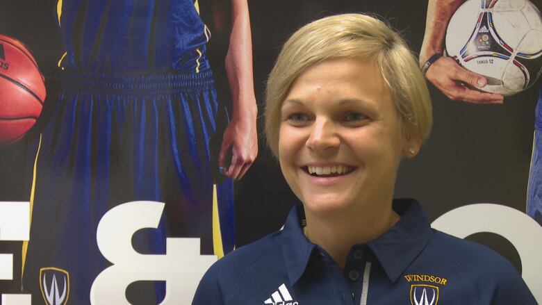 A woman with blonde hair wearing a dark blue polo shirt