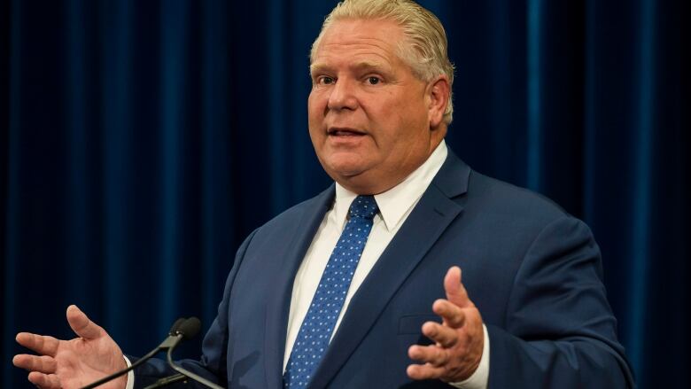 Man in a blue suit talking at a podium