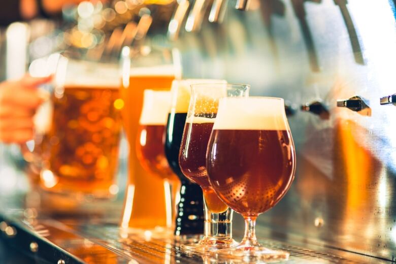 Glasses of beer are seen on a bar.