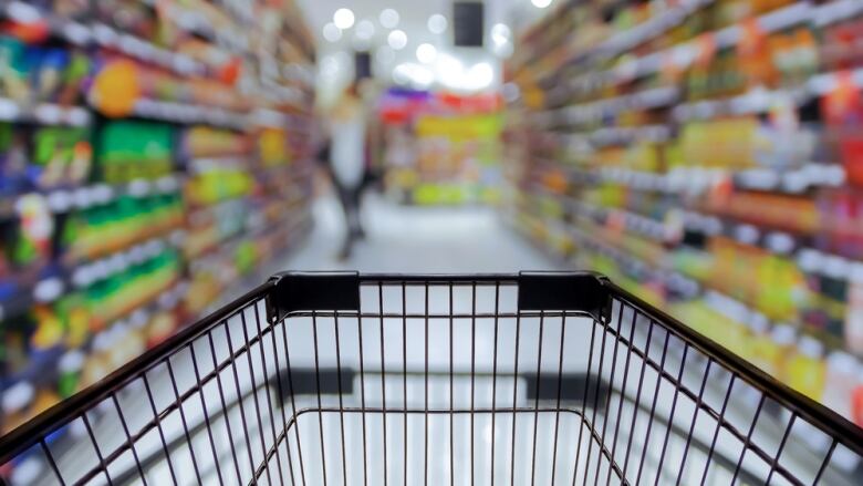 A stock image shows a shopping cart in the foreground with a grocery store aisle out of focus in the background.