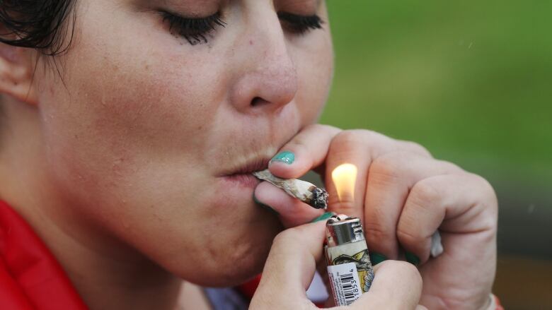 A woman lights a joint.