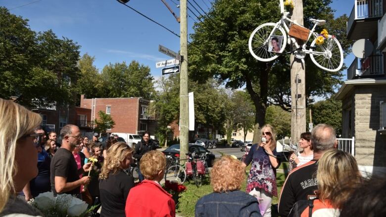 A white bike placed high above the ground on a pole. 