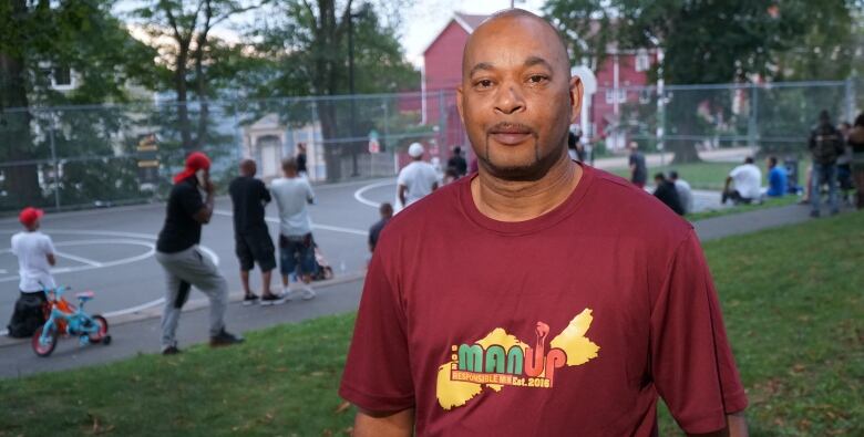 A man stands in front of an outdoor basketball court.