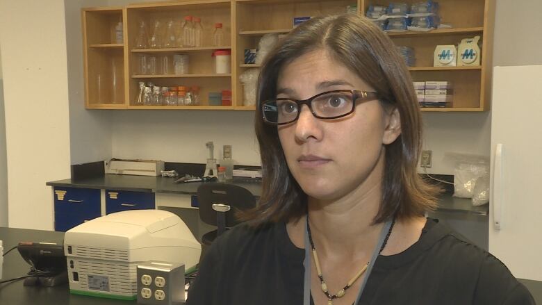 Woman in glasses standing in a science lab.