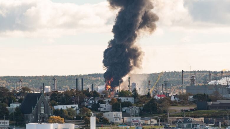 A thick billow of dark grey smoke shoots up over the city.