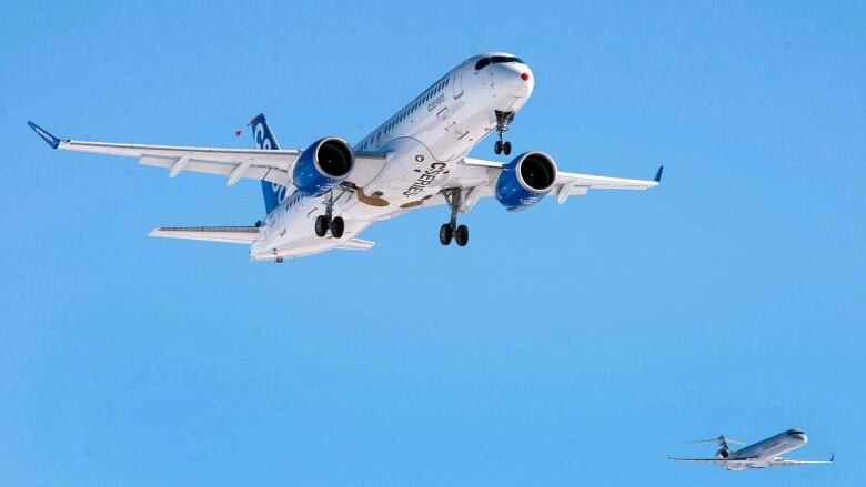 Two jets fly overhead in a blue sky. 